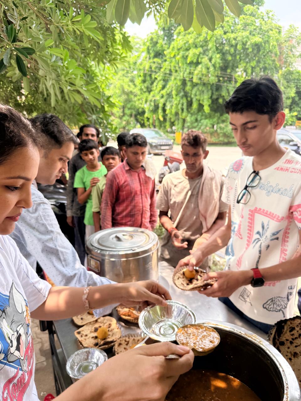 Volunteers preparing food plates while community members wait during the first drive.