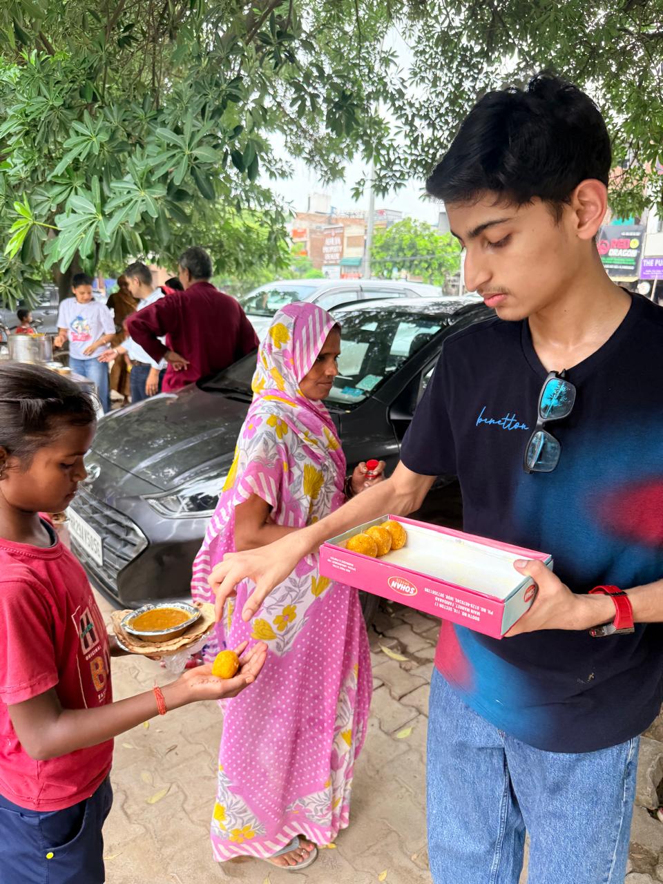 Jinanssh Jain handing food to a child during Nourish All on 4 August 2026.