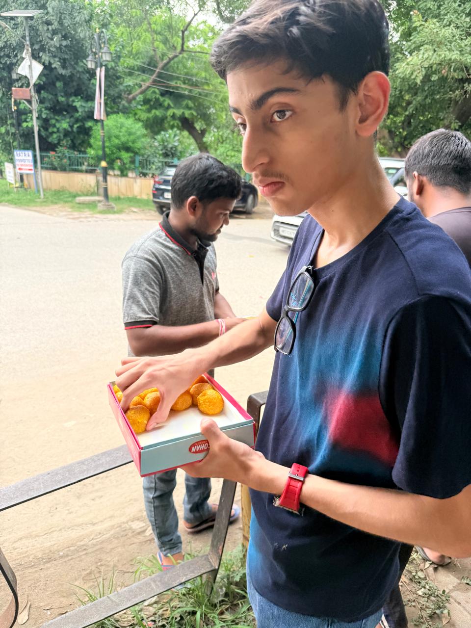 Jinanssh Jain holding a box of sweets during a close moment from Nourish All.