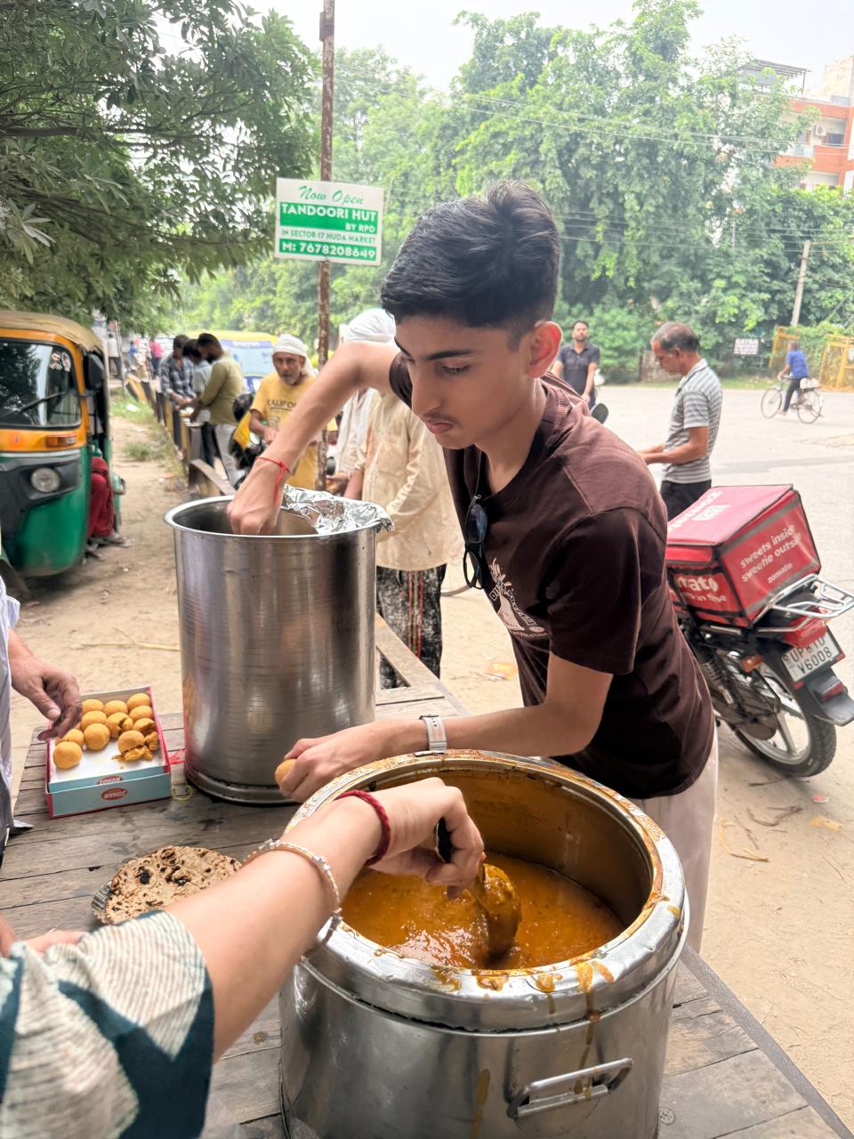 Jinanssh Jain preparing food plates as community members wait during Nourish All.