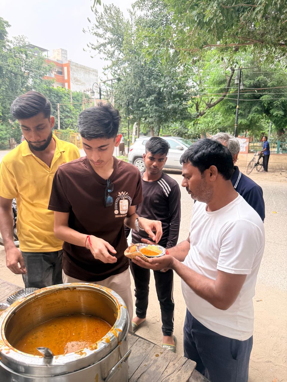 Jinanssh Jain handing a prepared meal to a community member during Nourish All.